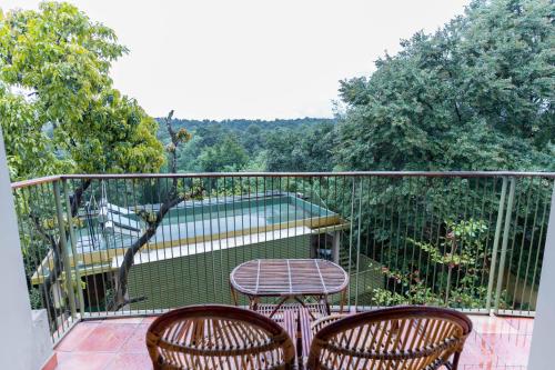 a balcony with two chairs and a table on a deck at Kuruva Island Resort And Spa - By KABINI BREEZE in Mananthavady