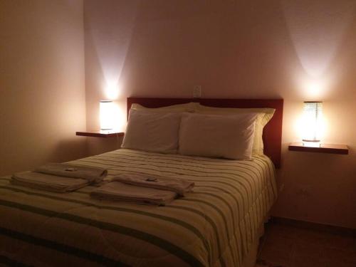 a bedroom with a bed with two lamps on it at Recanto dos Beija Flores, Chalé lantana e in Monte Alegre do Sul