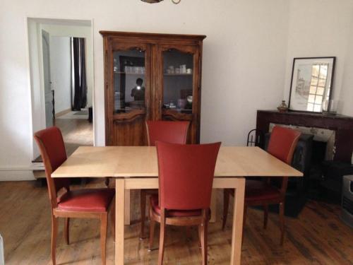 a dining room with a wooden table and red chairs at Gite 2 pers. Au Pied Du Vercors in Vinay