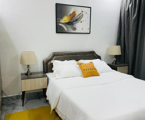 a bedroom with a bed with a yellow pillow on it at White villa apartment in Kigali