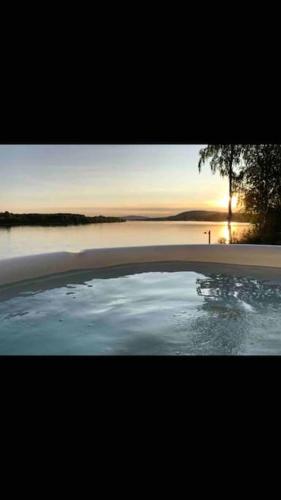 a view of a pool of water with the sun setting at Northern Lights exclusive house by the river in Boden