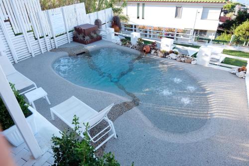 una piscina con sillas blancas, mesa y sillas en Pharus Miseni Suites and rooms, en Bacoli