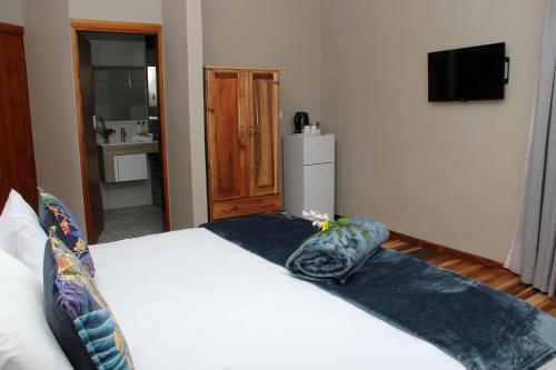 a bedroom with a large white bed and a refrigerator at Fairy Knowe Hotel in Wilderness