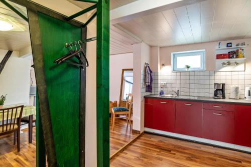 a kitchen with red cabinets and a green door at Ferienwohnung Blaues Haus in Ubstadt-Weiher