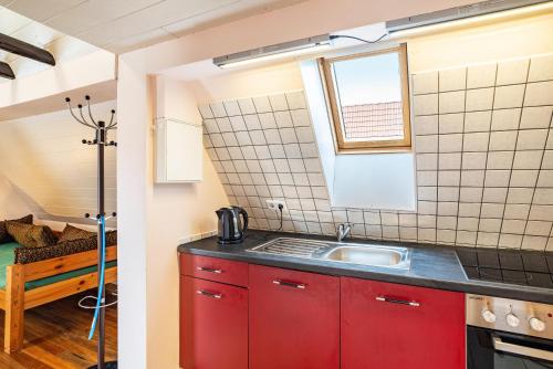 a kitchen with red cabinets and a sink at Ferienwohnung Blaues Haus in Ubstadt-Weiher