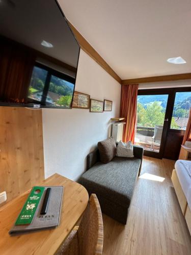 a living room with a couch and a table with a laptop at Landhotel Maiergschwendt inkl Chiemgaukarte in Ruhpolding