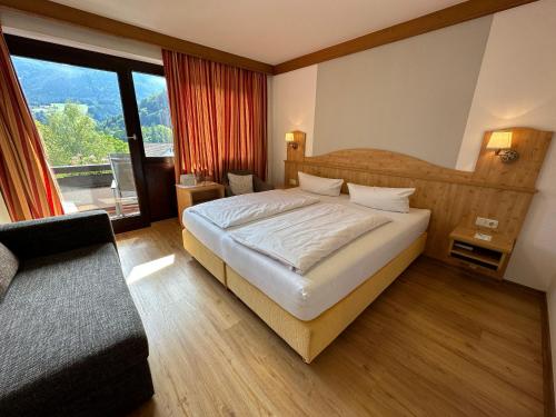 a bedroom with a large bed and a large window at Landhotel Maiergschwendt inkl Chiemgaukarte in Ruhpolding