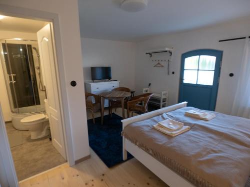 a bedroom with a bed and a table and a bathroom at Penzión Záruby in Smolenice