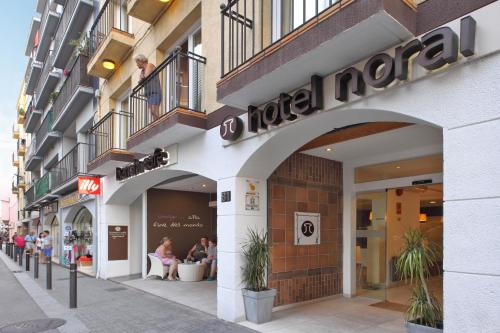 una tienda frente a un edificio con gente sentada afuera en Hotel Norai, en Lloret de Mar