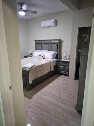 SG Apartment Complex (Apt #1) في Linstead: غرفة نوم مع سرير ونباتين ليلية وسرير سيد