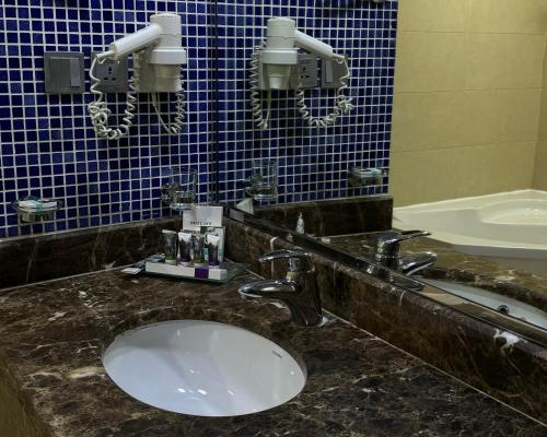 Mercure Jeddah Al Hamraa Hotel في جدة: حمام مع حوض والجدار الأزرق البلاط