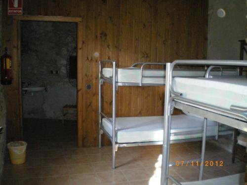 two bunk beds in a room with a bathroom at Albergue Casa Fumenal in Padarniu