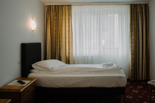 a bed in a hotel room with a window at Hotel Casa Pelerinul in Durau