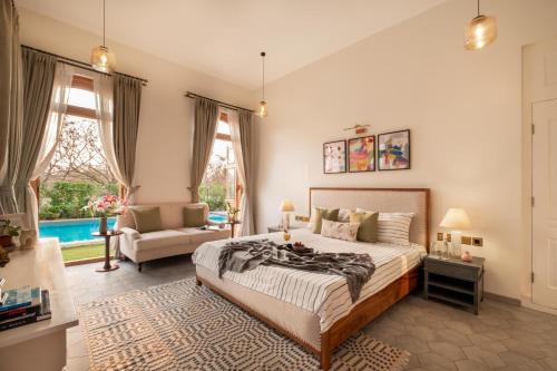 a bedroom with a bed and a couch and windows at LohonoStays Villa Sobreda in Bardez