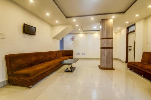 uma sala de estar com um sofá castanho e uma televisão em Collection O Hotel Aaradhya Heritage em Bodh Gaya