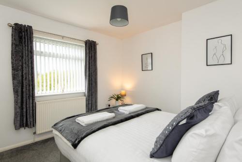 a bedroom with a white bed and a window at The Crescent in Witton Gilbert