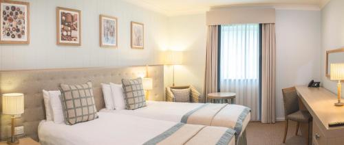 a hotel room with a bed and a desk at De Vere Cotswold Water Park in Cirencester