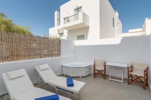a patio with white chairs and a table and a building at Eclipse Tales in Adamas