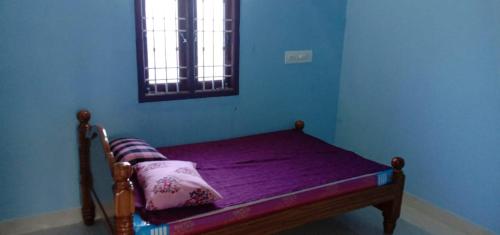 a bed with purple sheets in a blue room with a window at Arunachala Mountain View House in Tiruvannāmalai