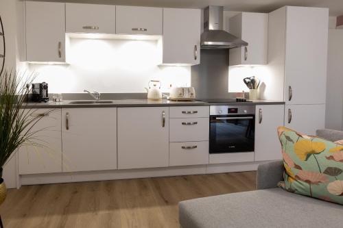 uma cozinha com armários brancos e um forno com placa de fogão em Regency Court em Southampton