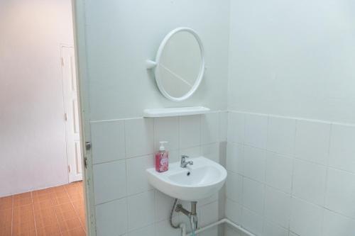 La salle de bains blanche est pourvue d'un lavabo et d'un miroir. dans l'établissement Baan Ragang : Cozy Entire House in Old Chiang Mai, à Chiang Mai