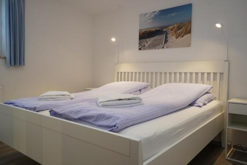 Una cama blanca con dos toallas encima. en Yildirim Touristik Wohnung L&L 7 en Duhnen