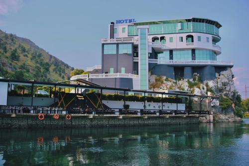 a building on the side of a river next to a building at Prince of Lake Hotel in Shkodër