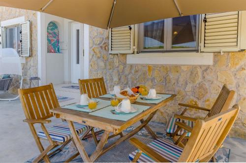 une table en bois avec des chaises et un parasol dans l'établissement Apartments Vila Jelka, à Vrboska