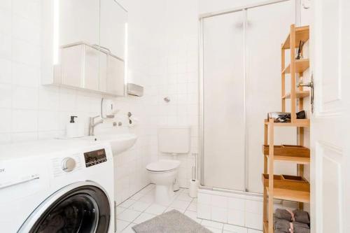biała łazienka z pralką i toaletą w obiekcie Newly furnished apartment for up to 6 people w Berlinie