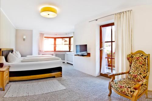 um quarto com uma cama, uma cadeira e uma televisão em ZugspitzApps em Ehrwald