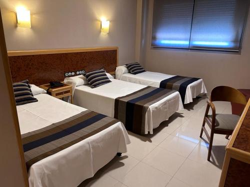 una habitación de hotel con 3 camas y una silla en Hotel Escuela San Cristobal, en La Cistérniga