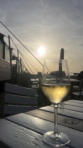 a glass of white wine sitting on a table at La Cabane de la mer in Bredene
