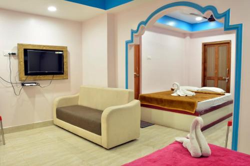 a bedroom with a bed and a chair and a tv at Sree Karpagam Dreams in Port Blair