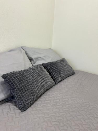 a bed with a gray pillow on top of it at Amot apartamentai in Telšiai