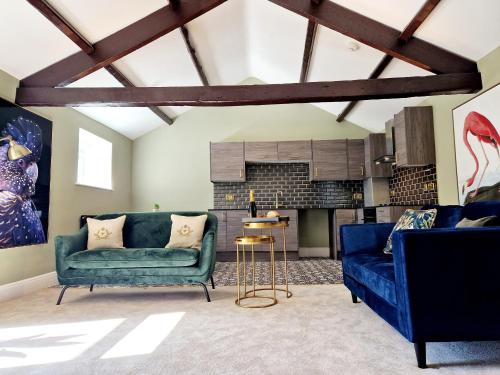 a living room with two blue couches and a kitchen at The Cruck in Preston