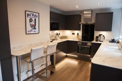 a kitchen with black cabinets and white counter tops at Shrewsbury Townhouse - Free Parking in Shrewsbury