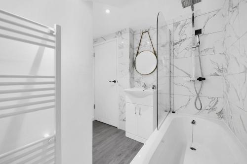 a white bathroom with a sink and a mirror at Cool 2 Bed Basement Flat in Central Shoreditch! in London