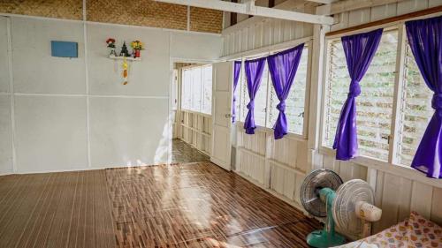 een lege kamer met paarse gordijnen en een ventilator bij Mountain Campsite kanchanaburi 