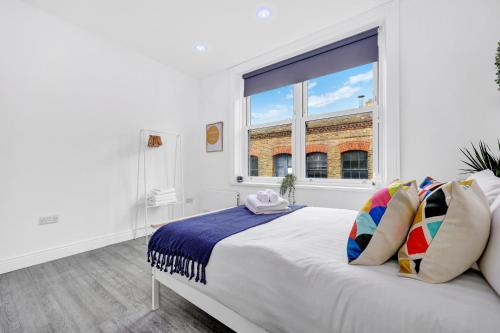 - une chambre blanche avec une grande fenêtre et un lit dans l'établissement Central Hoxton High Spec 2 Bed!, à Londres
