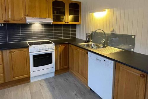 a kitchen with wooden cabinets and white appliances at Leitane 2 Bremanger in Fossane