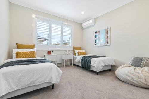 1 Schlafzimmer mit 2 Betten, einem Tisch und einem Fenster in der Unterkunft Spacious Luxury Hampton Home - Park Front in Melbourne