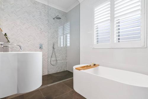 ein weißes Bad mit einer Badewanne und einer Dusche in der Unterkunft Spacious Luxury Hampton Home - Park Front in Melbourne