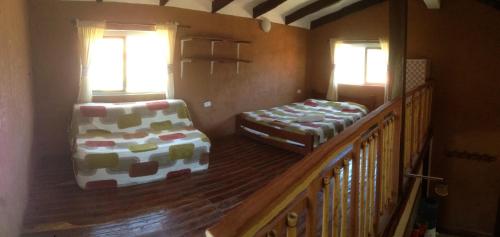 a room with two beds and a chair in a house at Casa Amanecer in Samaipata