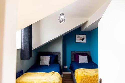 two beds in a room with blue walls at Emerald Gem of Leeds with Great Location including Parking in Killingbeck
