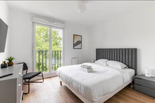 a white bedroom with a large bed and a desk at StadeDeFrance/Saint-Denis : Appartement Terrasse 6P in Saint-Denis