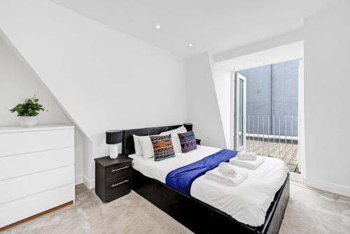 a white bedroom with a bed and a window at Loft apartment in Broadway Market in London