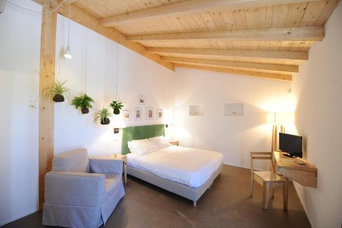 a bedroom with a bed and a chair and a tv at Montegusto in Castel del Monte