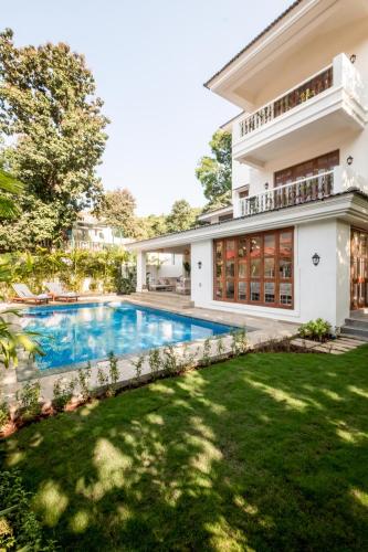 an exterior view of a house with a swimming pool at LohonoStays Villa Athena in Siolim