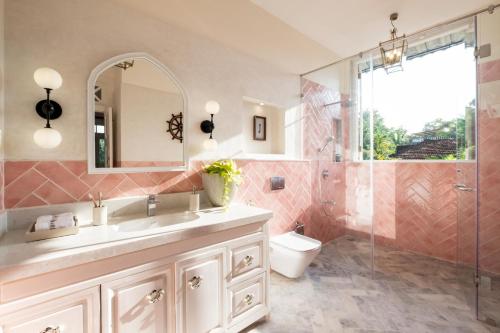 a bathroom with a sink and a toilet and a mirror at LohonoStays Villa Athena in Siolim