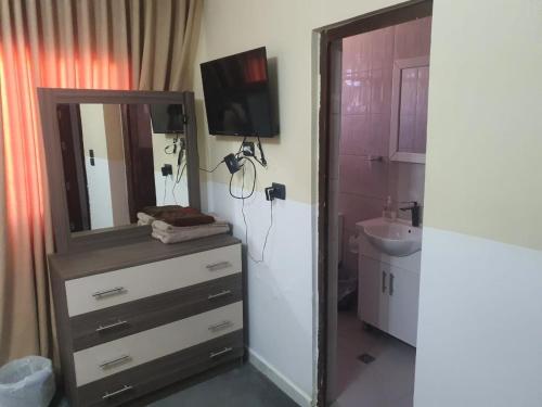 La salle de bains est pourvue d'une commode avec un miroir et un lavabo. dans l'établissement Alfares Hotel, à Tufailah